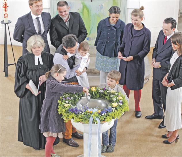 Taufe als Neugeburt im Glauben: In der Dorfkirche Lohmen (Sächsische Schweiz) wird ein Kind getauft. Die Schwester des Täuflings gießt das Wasser aus der Taufkanne in die Taufschale. Eltern und Paten begleiten die Zeremonie. Foto: epd-bild/Rainer Oettel 