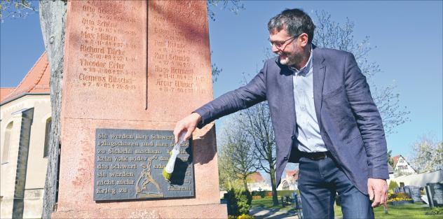 Pfarrer Christoph Rechenberg am Friedensmahnmal vor der Kirche Naustadt