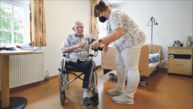 Anja Morgenstern mit Heimbewohner Juergen Boehme im Seniorenheim »Haus Elisabeth« in Freiberg. Die Pflegefachkraft ist skeptisch gegenüber dem Corona-Impfstoff und will sich nicht impfen lassen. Foto: epd-bild/Matthias Rietschel Pflege, Impfpflicht, Betreuung, Seniorenheim, Freiberg