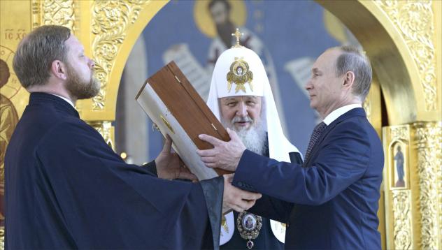 Nähe von Staat und Kirche: Patriarch Kyrill von Moskau (hinten) lässt Präsident Putin (r.) eine Ikone des Hl. Wladimir überreichen (2015). Foto: Chyornyy chelovek/CC BY-SA 4.0