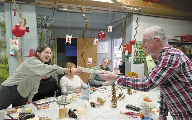 Koordinatorin Corinna Franke überreicht zur Adventsfeier der Freiwilligenzentrale der Diakonie Leipziger Land in Grimma ein kleines Dankeschön-Geschenk an Familienpaten Mario Engler. © Diakonie Leipziger Land
