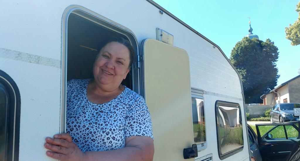 Laima Kranz und ihr Mann aus Baden-Württemberg haben nach langer Fahrt auf dem Parkplatz neben der Autobahnkirche die Nacht im Camper verbracht. Die Kirche (im Hintergrund) wollten sie sich noch ansehen. © K. König