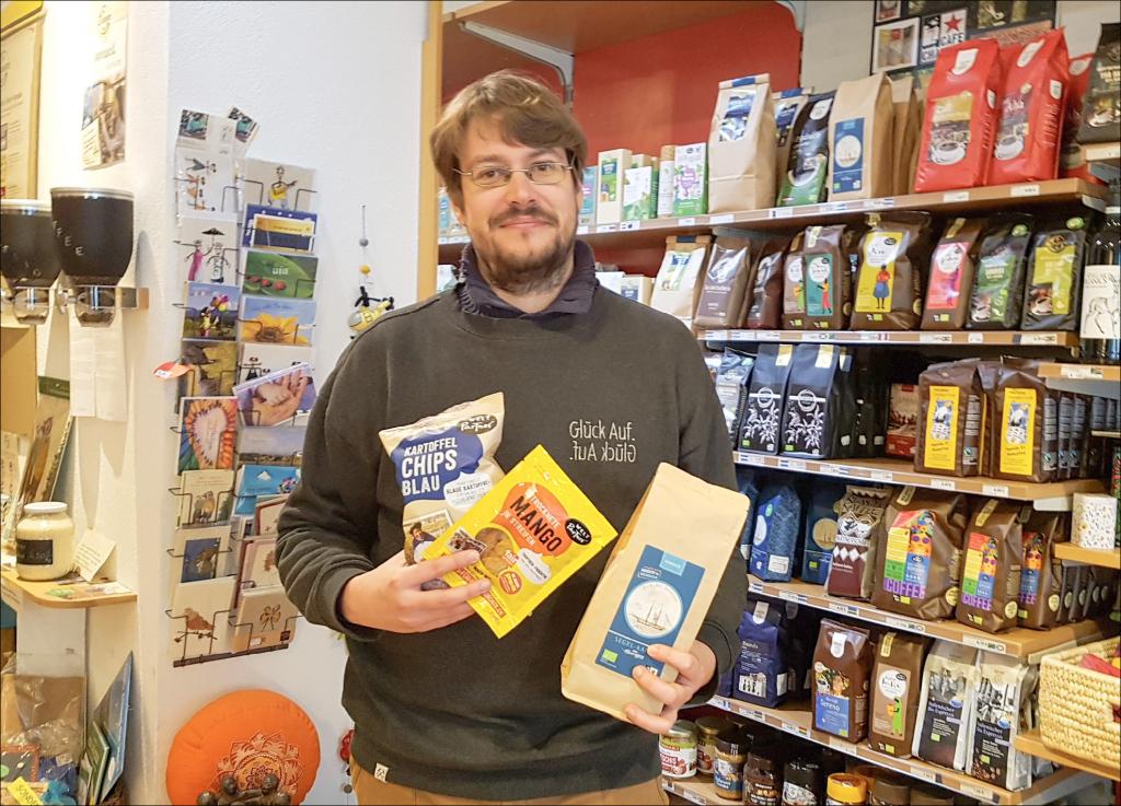 Christian Mädler hält im Weltladen in Freiberg Kaffee, Mangostreifen und Chips in den Händen: Alles natürlich fair gehandelt und erarbeitet von Kooperativen, die die Arbeits- und Lebensbedingungen vor Ort verbessern helfen. © Uwe Naumann