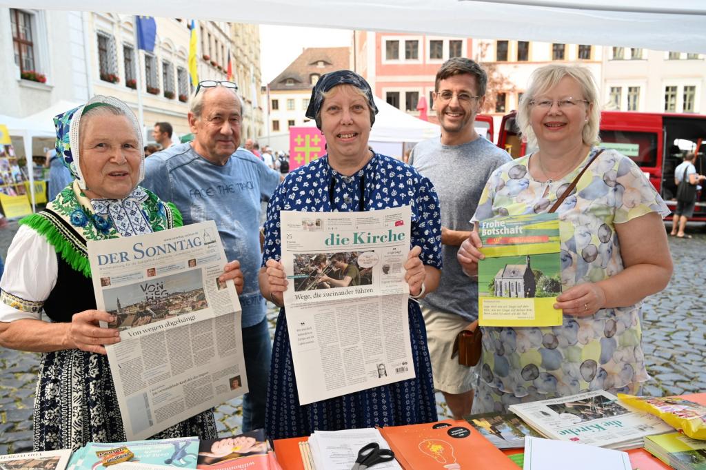 Die Kirchenzeitung mittendrin: Begegnung am Gemeinschaftsstand von DER SONNTAG und DIE KIRCHE auf dem Markt der Möglichkeiten – mit Redakteurin Sibylle Sterzik (r.), Stefan Seidel (2. v. r.) und Sorbinnen aus Schleife. © Steffen Giersch