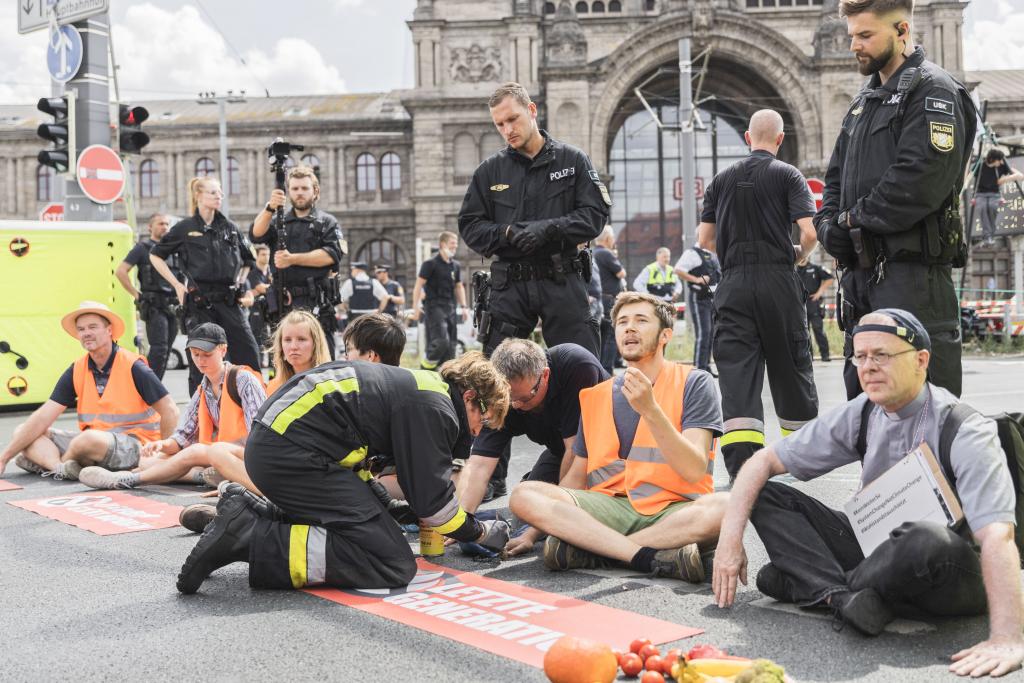 Radikal für das Klima: Der Nürnberger Jesuitenpater Jörg Alt (r.) klebte sich am 16. August im Rahmen einer Straßenblockade von Klimaschützern mit der Hand am der Straße fest. © epd-bild/Valeska Rehn