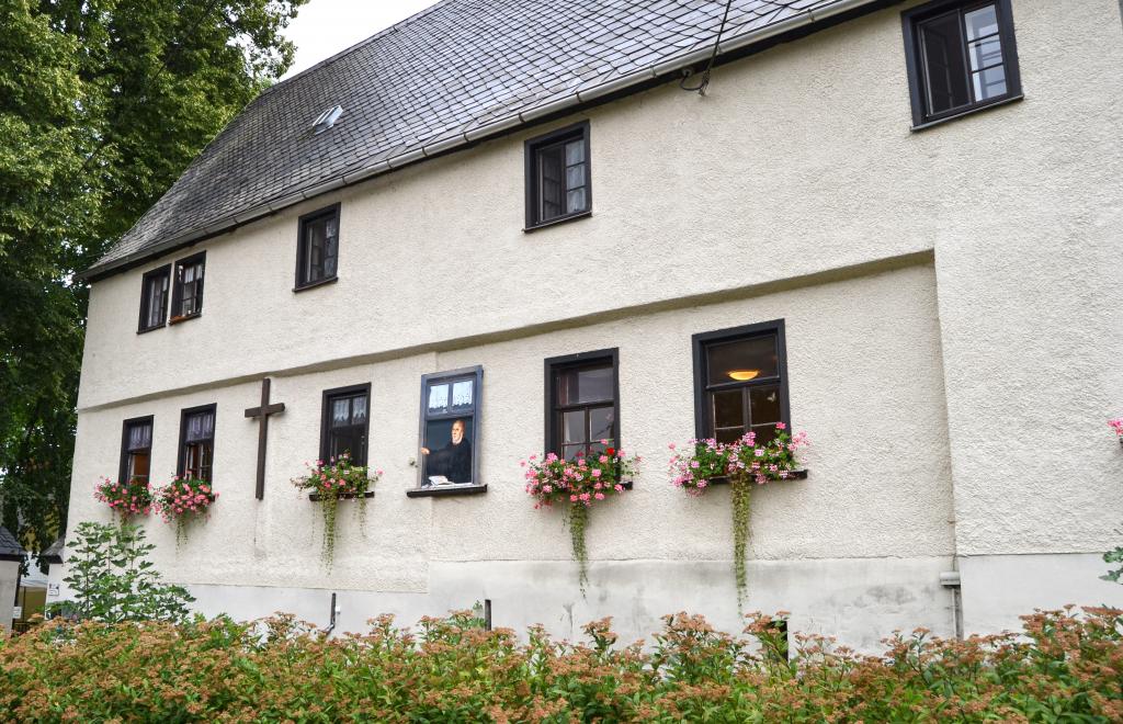 Am Pfarrhaus zeigt Luther auf das Jesuskreuz. © Karola Richter