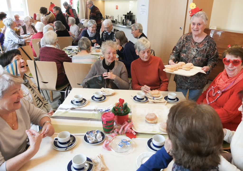 Ältere Frauen und Männer in frohem Austausch bei Pfannkuchen und Kaffee. Der Nachmittag zu Rosenmontag gehörte zum Programm des »Netzwerks 60+« in Dresden. © Tomas Gärtner