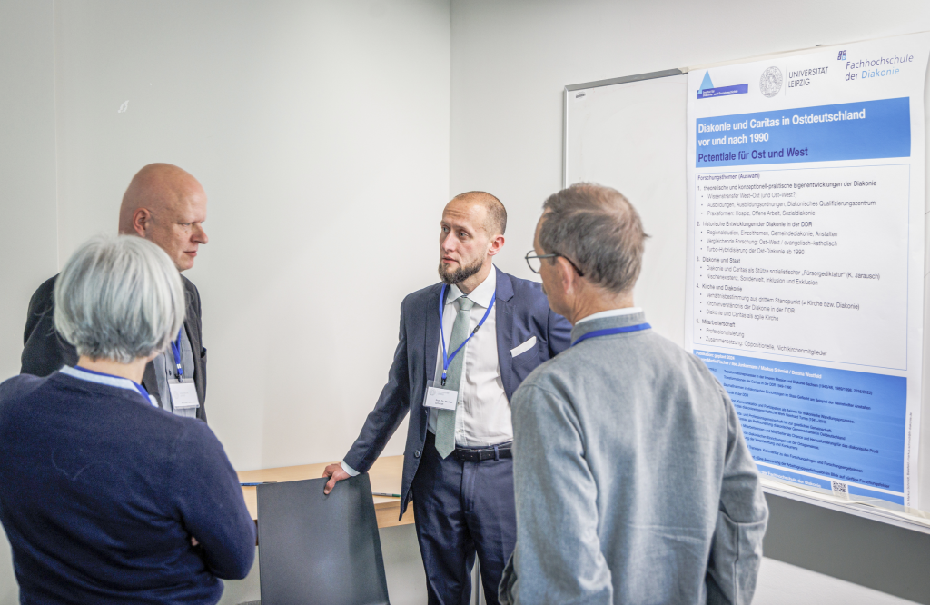 Gesprächsgruppe am Plakat bei Prof. Dr. Markus Schmidt (2.v.r.) zum Thema Diakonie und Caritas. © Uwe Winkler