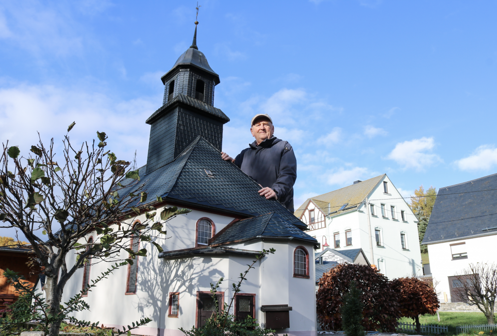 Günter Müller an der Mini-Kirche in Mini-Weißbach. Er hat sie kürzlich mit anderen generalüberholt. Das sind Nachbauten von wichtigen Gebäuden des Ortes. 51 Stationen gehören zum Krippenweg. © Irmela Hennig