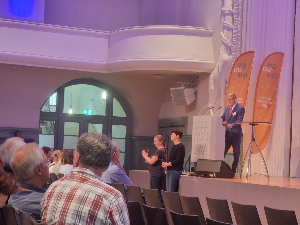 Präsident Vollbach eröffnet die Veranstaltung mit mutmachenden Worten, offen miteinander und mit den Mitarbeitern des Landeskirchenamtes ins Gespräch zu kommen. Unterstützt werden Referentinnen und Referenten durch Gebärdensprache. © Karola Richter