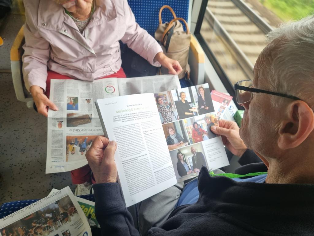 Im Zug wird der druckfrische Sonntag gelesen, genau wie die anderen Zeitungen und Material der Sponsoren, wie der KD Bank. © Karola Richter 