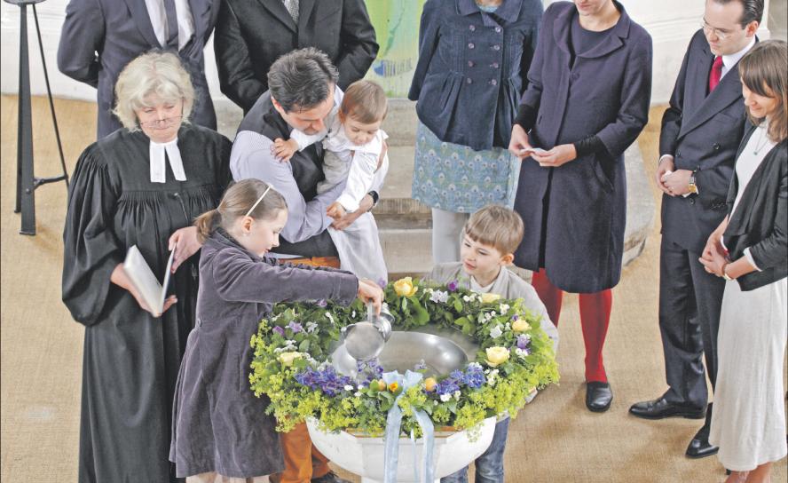 Taufe als Neugeburt im Glauben: In der Dorfkirche Lohmen (Sächsische Schweiz) wird ein Kind getauft. Die Schwester des Täuflings gießt das Wasser aus der Taufkanne in die Taufschale. Eltern und Paten begleiten die Zeremonie. Foto: epd-bild/Rainer Oettel 