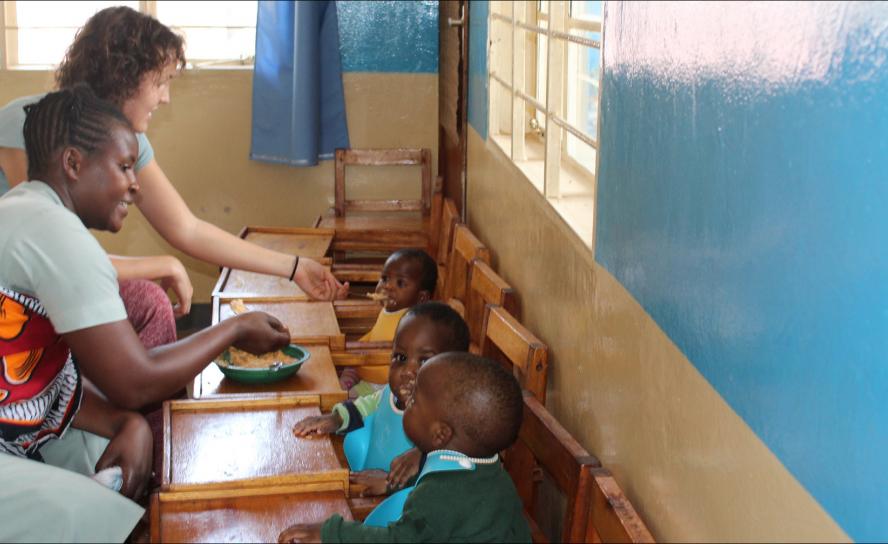 Freiwilligeneinsatz im Ausland: Anna Siegmund und Tarisila Kayombo füttern Jaqueline, Ayubu und Ema mit Brei aus Ugali, Ei und Tomate im Kinderhaus des lutherischen Krankenhauses in Ilembula (Tansania).