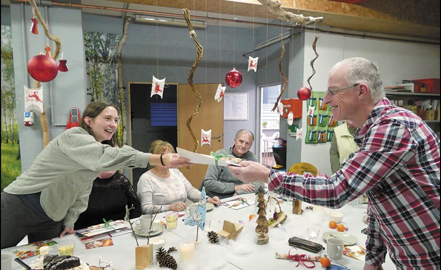 Koordinatorin Corinna Franke überreicht zur Adventsfeier der Freiwilligenzentrale der Diakonie Leipziger Land in Grimma ein kleines Dankeschön-Geschenk an Familienpaten Mario Engler. © Diakonie Leipziger Land