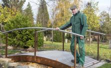 Friedhofsverwalter Hartmut Schneider steht auf einer Brücke des neuen Trauerwegs auf dem Friedhof in Dresden-Cotta. Schneider möchte damit Trauernde ansprechen sowie zum Spaziergang auf dem Friedhof einladen. Foto: Dietrich Flechtner