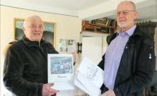 Die Kriege nicht vergessen: Claus Walkowiak (l.) und Helmut Wirth vom Museumsverein Harra im Vogtland zeigen das neue Buch “Ein Gruß an unsere Lieben im Felde” mit Kirchenblättern aus dem 1. Weltkrieg. 